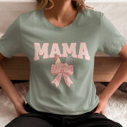 Woman sitting cross-legged wearing a sage green "Chicken Mama" t-shirt with a coquette-inspired design featuring a rooster and floral bow, printed on a Comfort Colors 1717 shirt.